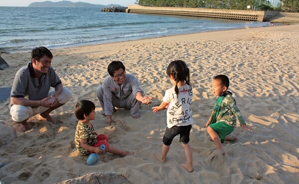 가와구치 마사토 원장과 와쿠와쿠 보육원 아이들이 일본 이토시마시의 해변가에서 놀고 있다.