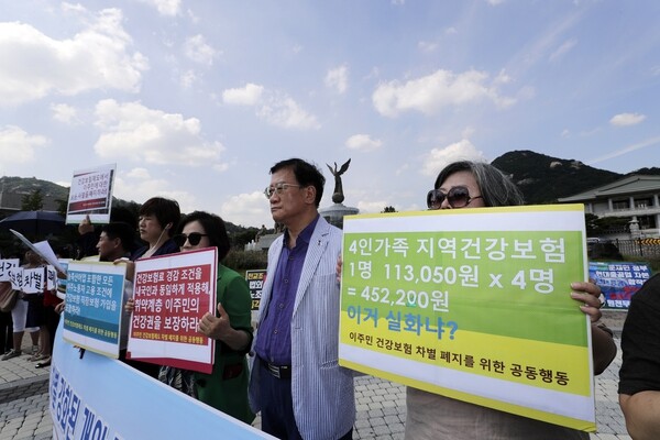 Groups with the organization Collective Action to Abolish Health Insurance Discrimination against Migrants hold a press conference in front of the Blue House on the afternoon of Aug. 26 to denounce the health insurance system’s increased discrimination against migrants. (Kim Myoung-jin