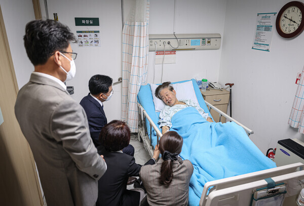 Democratic Party leader Lee Jae-myung speaks with Jin Gyo-hoon, the Democratic Party’s candidate for mayor of Seoul’s Gangseo District, in his room at Green Hospital in Seoul’s Jungnang District on Sept. 22. (courtesy of the Democratic Party)