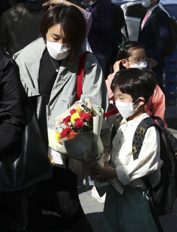 A student at an elementary school in Seoul’s Songpa District accepts a bouquet of flowers from his mother on May 27. (Yonhap News)