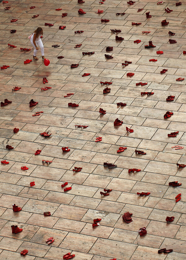 2015년 6월 젠더폭력·페미사이드에 반대하기 위해 스페인 말라가에 전시된 설치미술 작품 앞에서 한 여성이 풍선을 잡으려 하고 있다. 광장에는 살해된 여성들을 상징하는 745개의 붉은 구두가 놓여 있다. REUTERS.