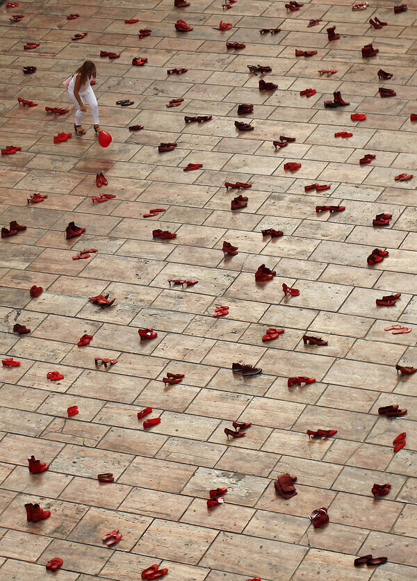 A woman bends to catch a balloon amid an art installation by Elina Chauvet in La Constitucion Square in Malaga, southern Spain, protesting gender violence and femicide in June 2015. The square is filled with 745 pairs of red shoes. (Reuters)