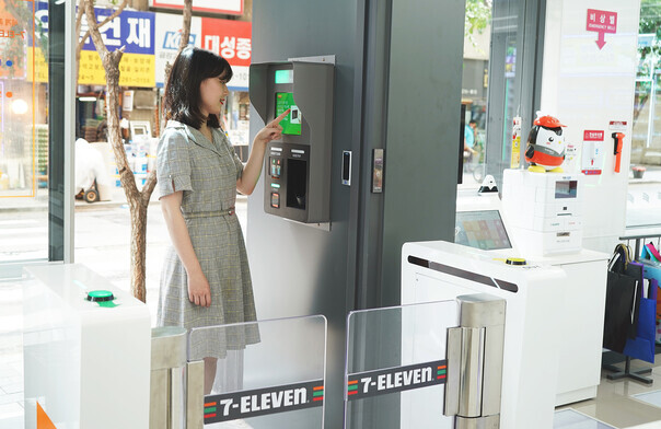 A customer at an automated convenience store verifies her identity via credit card and has her photo taken by a CCTV camera. (provided by 7-Eleven)