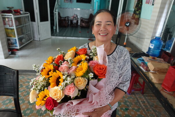 Nguyễn Thị Thanh, a survivor of Korea’s massacres in Vietnam, smiles as she holds a bouquet given to her by young Koreans on Feb. 12 celebrating her victory in a suit suing the Korean government for compensation. (Shin Da-eun/The Hankyoreh)