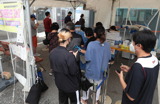 People wait in line to be tested for COVID-19 at a screening station in Seoul on July 5. (Kang Chang-kwang/The Hankyoreh)