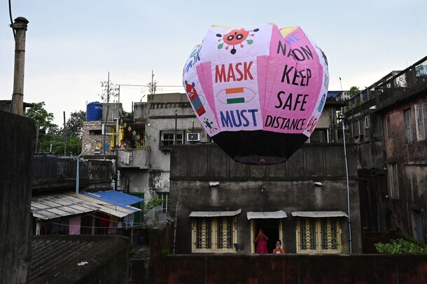 Residents take pictures of a paper lantern released with Covid-19 guidelines in Kolkata on Tuesday. (AFP/Yonhap News)
