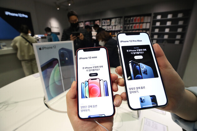 People hold up two iPhone 12 models at a store upon their release in Korea in November 2020. (Yonhap)