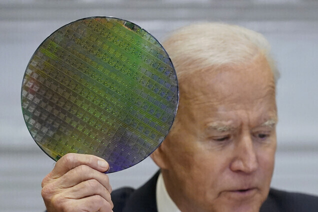 US President Joe Biden holds up a silicon wafer, as he participates virtually in the CEO Summit on Semiconductor and Supply Chain Resilience on April 12 in the White House. (AP/Yonhap News)