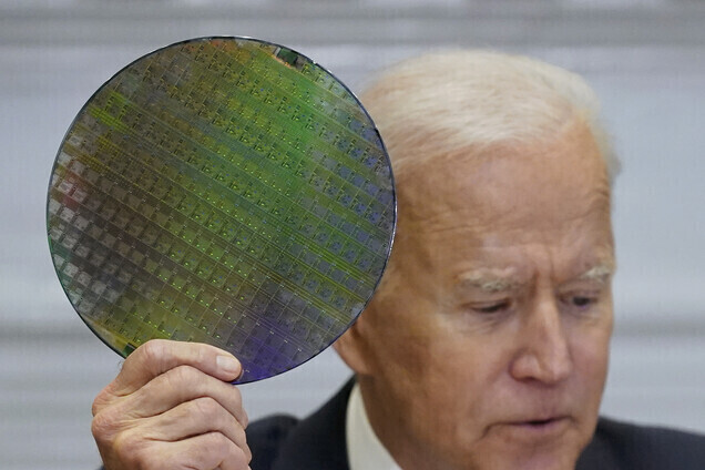 US President Joe Biden holds up a silicon wafer as he participates virtually in the CEO Summit on Semiconductor and Supply Chain Resilience in the White House on April 12. (AP/Yonhap News)
