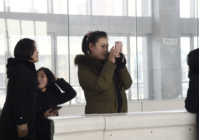 A Pyongyang resident takes a photo of the city’s outdoor ice rink on Feb. 11. (Yonhap News)