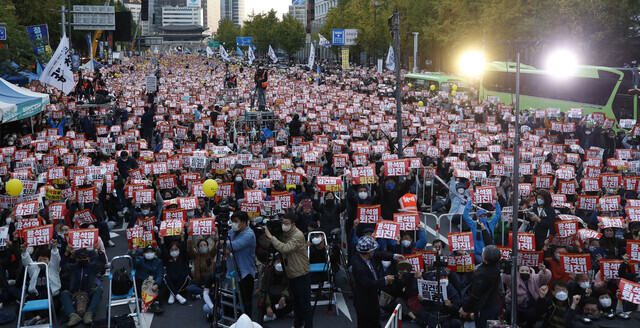 People participating in a rally organized by Candlelight Action in downtown Seoul hold up pickets and chant on Oct. 22. (Kim Hye-yun/The Hankyoreh)