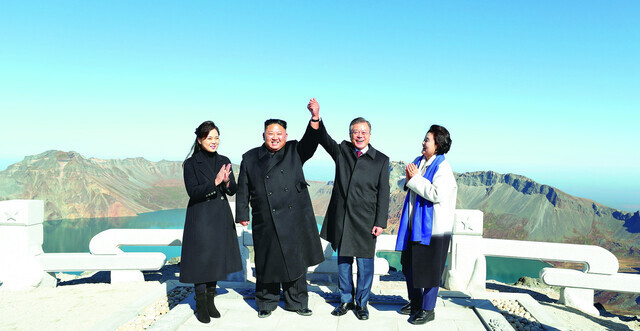 South Korean President Moon Jae-in and North Korean leader Kim Jong-un clasp hands and raise them high over their heads at the top of Mount Baekdu on Sept. 20, 2018. (pool photo)