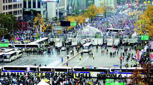 Police fire water cannons at demonstrators from across a police wall at Gwanghwamun Square in central Seoul