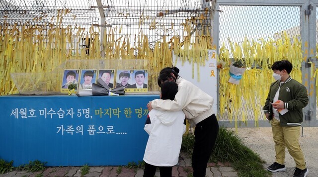 People stand before a memorial for those missing from the 2014 sinking of the Sewol Thursday ahead of the disaster’s seventh anniversary Friday. (Kim Bong-gyu/The Hankyoreh)