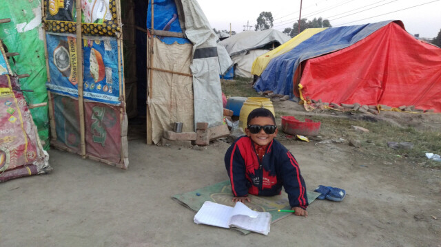 네팔 추체파티 이재민 임시거주지에서 만난 선조크가 텐트 밖 맨바닥에서 숙제를 하고 있다.