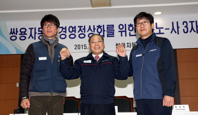 Ssangyong Motor CEO Choi Jong-sik (center) celebrates the signing of a labor agreement with KMWU’s Ssangyong chapter leader Kim Deuk-jung (left) and Ssangyong labor union leader Hong Bong-seok (right)