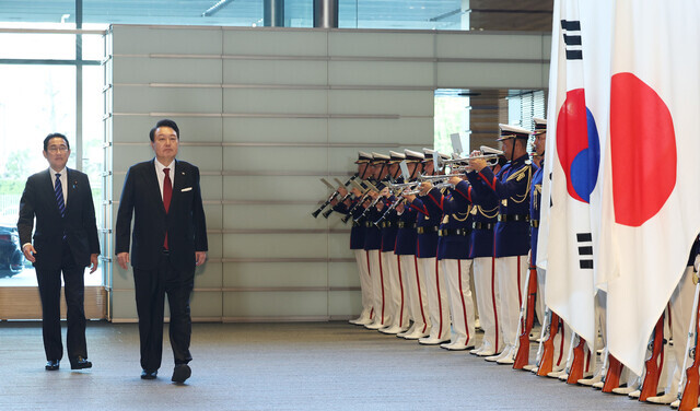 President Yoon Suk-yeol of South Korea and Prime Minister Fumio Kishida of Japan make their way past the color guard ahead of their summit in Tokyo on March 16. (Yonhap)