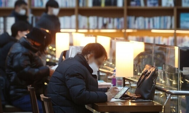 People wearing face masks sit at desks in a shopping mall in Seoul in December 2022. (Yonhap)