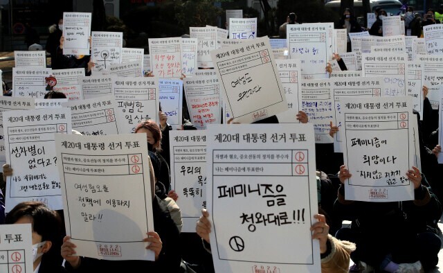 Participants in the “2022 Feminist Voters Action” hold a rally in central Seoul on Feb. 12, where they hold up signs with their messages to presidential candidates. (Park Jong-shik/The Hankyoreh)