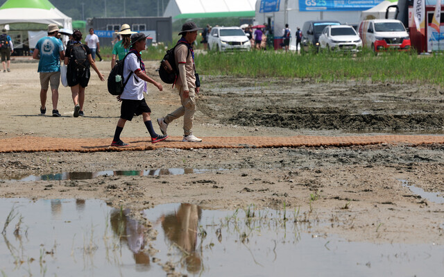 Participants in the 2023 World Scout Jamboree walk on a trail next to a patch of waterlogged mud on Aug. 1. (Yonhap)