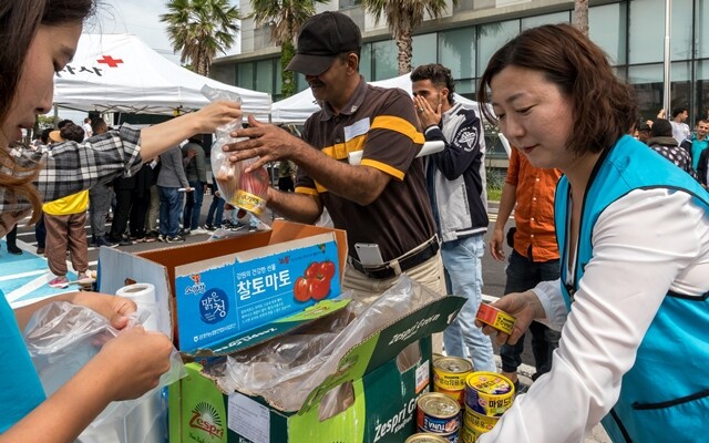 비영리 시민사회단체인 글로벌이너피스 자원봉사자들이 6월18일 제주출입국·외국인청사에서 예멘 난민에게 과일과 빵 등 먹을 것을 나눠주고 있다.