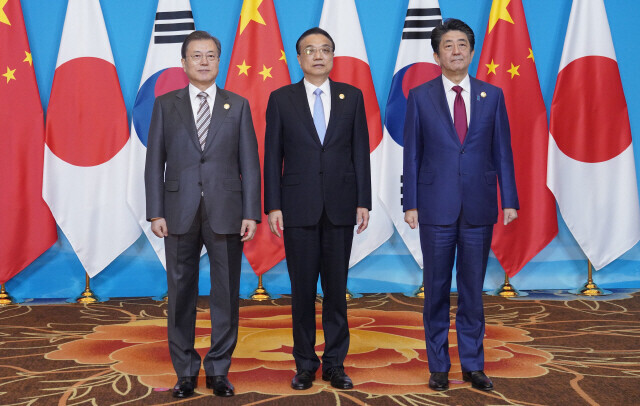 South Korean President Moon Jae-in, left, poses for a picture with then-Japanese Prime Minister Shinzo Abe, right, and Chinese Premier Li Keqiang at a trilateral summit on Dec. 24, 2019. (Blue House photographers’ pool)