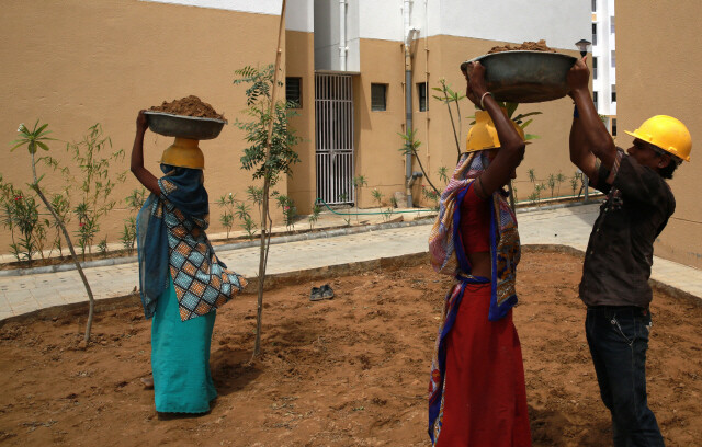 인도 타타그룹이 구자라트주 아마다바드 북쪽 간디나가라 외곽에 짓고 있는 ‘어포더블 하우스’ 건설 현장에서 여성 노동자들이 대야로 흙을 나르고 있다.