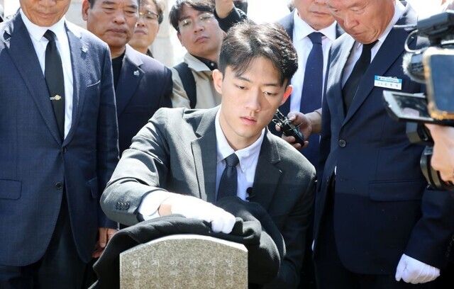 Chun Woo-won, the grandson of the late dictator Chun Doo-hwan, wipes down the gravestone for Kim Kyeong-cheol, a martyr of the democratic uprising that was brutally quashed by Chun Doo-hwan in May 1980 in Gwangju, during a visit to the May 18th National Cemetery on March 31. (pool photo)