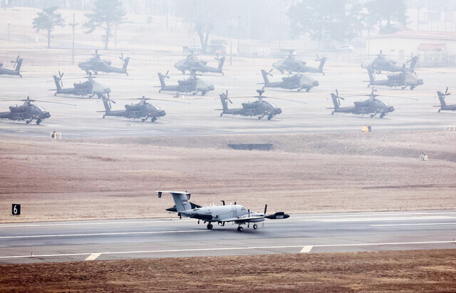 An RC-12X Guardrail spy plane lands at the US base of Camp Humphreys in Pyeongtaek, Gyeonggi Province, on March 3, 2024, one day before the joint South Korea-US Freedom Shield exercises were set to kick off. American Apache attack helicopters sit on the field next to the runway. (Yonhap)