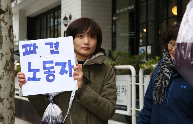 이영숙씨가 지난 11월26일 서울 강남 ㅅ제약 본사 앞에서 ‘파견노동자’라고 쓰인 팻말을 들었다. 영숙씨는 ‘불법파견’으로 자신을 고용했다가 해고한 ㅅ제약을 상대로 ‘직접고용’을 요구하며 싸우고 있다. 류우종 기자