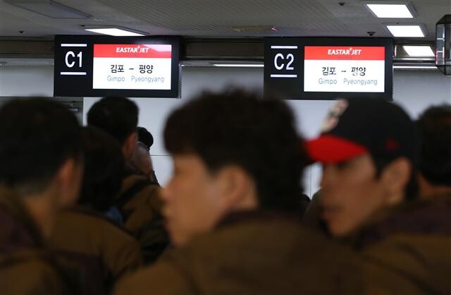 Workers from South Korea’s two main umbrella unions check in for their flight to Pyongyang