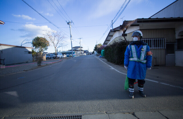 후쿠시마 곳곳에서 높은 방사선량 때문에 접근이 통제된 지역을 찾을 수 있다. 한 경비원이 ‘귀환곤란구역’을 지키고 있다.