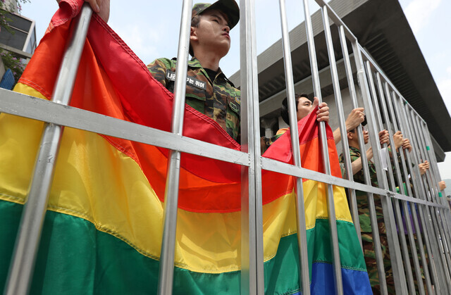 Sexual minorities don military uniforms and carry a rainbow flag as they protest and call for an end to the punishment of soldiers for same-sex sex acts on July 5, 2017, outside of the Sejong Center in Seoul. (Yonhap)