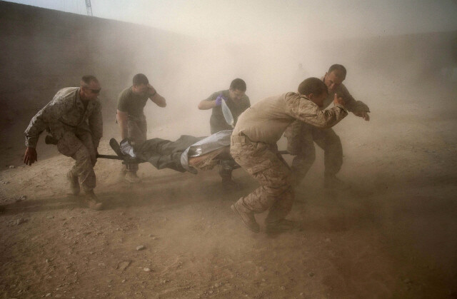 2011년 5월 아프가니스탄 남부 산간 지역에서 미 해병대가 폭발물에 부상당한 동료를 헬리콥터가 일으킨 먼지를 뚫고 옮기고 있다. AP 연합뉴스