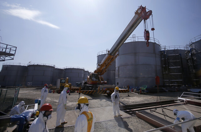 일본 후쿠시마 제1원전에 있는 오염수 저장탱크 근처에서 방호복을 입은 직원들이 일하고 있다. REUTERS