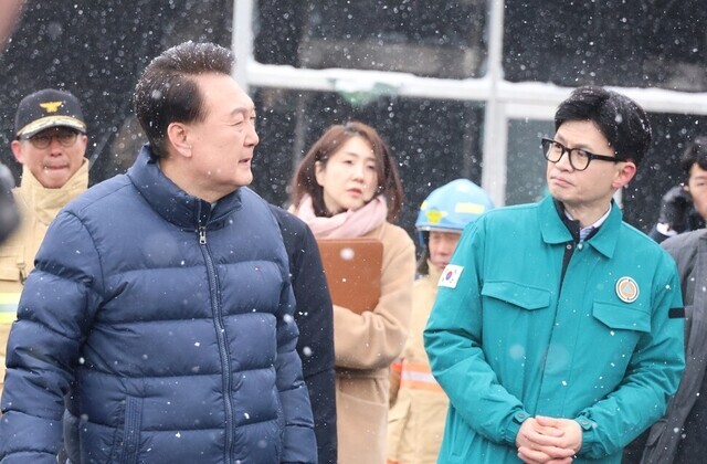 President Yoon Suk-yeol (left) and People Power Party interim leader Han Dong-hoon (right) survey damage to a market in Seocheon County, South Chungcheong Province, on Jan. 23, 2024, following a fire there. (Yonhap)