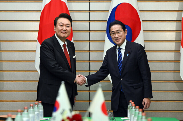 President Yoon Suk-yeol of South Korea (left) shakes hands with Prime Minister Fumio Kishida of Japan ahead of their summit in Tokyo on March 16. (Yonhap)