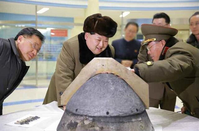 North Korean leader Kim Jong-un looks during field guidance at an object that appears to be a ballistic missile warhead