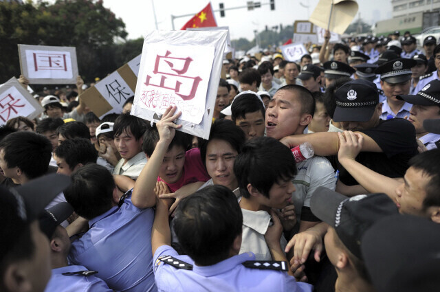 During a period of strained China-Japan relations, Chinese workers at Japan’s Meiko Electronics Co. Ltd. in Wuhan attempt to break through a police line around an area of Japanese residents in September 2012. (AP/Yonhap News)