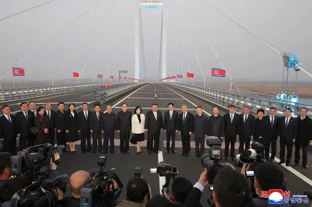 North Korean and Chinese officials stand for a photo on the newly opened New Yalu River Bridge connecting North Korea’s Sinuiju and China’s Dandong during an unannounced day trip to China on Oct. 24, 2026. (KCNA/Yonhap)