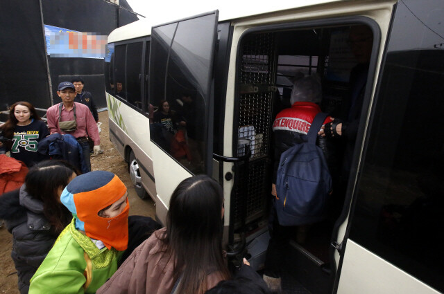 단속반에 체포돼 수갑을 찬 미등록 이주노동자들이 호송버스에 오르고 있다.