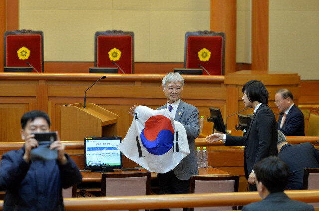 대통령 대리인단인 서석구 변호사가 2월14일 헌법재판소 대심판정에 들어서자마자 가방에 넣어온 ‘태극기’를 꺼내 펼쳐보이고 있다. 사진공동취재단