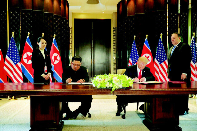 North Korean leader Kim Jong-un and US President Donald Trump sign a joint statement in Singapore during their first summit on June 12, 2018. Behind them are Kim’s younger sister Kim Yo-jong and US Secretary of State Mike Pompeo.