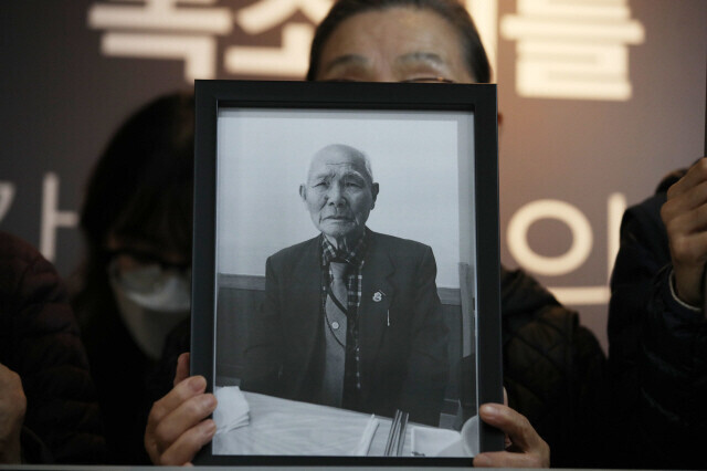Lee Hee-ja, a representative of an association advocating for reparations for those victimized during the Pacific War, holds up a photo of forced labor victim Lee Chun-sik during a press conference by civic organizations and victims of forced labor mobilization by Japan held at the Museum of Japanese Colonial History in Korea in Seoul’s Yongsan District on Oct. 28, 2021. (Kim Hye-yun/The Hankyoreh)