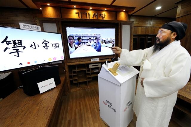  the schoolmaster uses an electronic blackboard and remote video technology to teach Chinese characters and etiquette to foreign students in Seoul. (provided by KT)