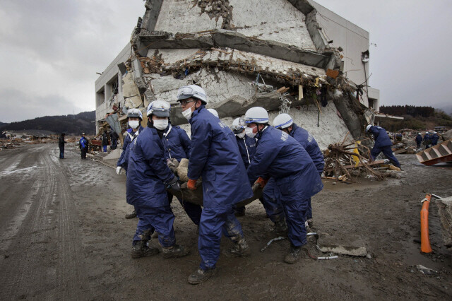 2011년 3월 동일본 대지진 때 경찰관들이 무너진 건물에서 희생자의 주검을 옮기고 있다. 일본에서는 사회적 약자들이 배제되는 고령자 지배체제인 ‘제론토크라시’가 지진 복구 과정에서 극명하게 드러났다. REUTERS