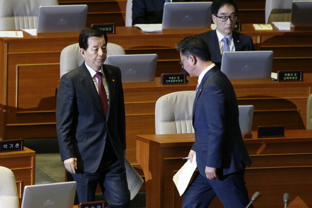 Minister of Unification Hong Yong-pyo (right) passes Defense Minister Han Min-koo as he goes up to answer questions at a National Assembly hearing in Seoul