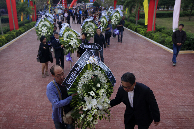 Members of a South Korean delegation move wreaths of flowers sent from South Korea to a memorial ceremony marking the fiftieth anniversary of a massacre of civilians by South Korean troops during the Vietnam War in Go Dai Village