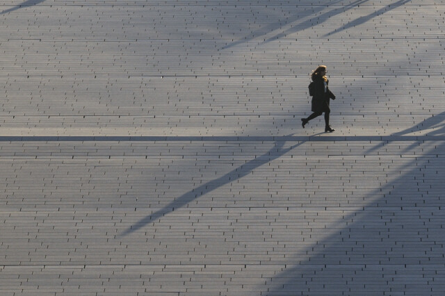 A student casts a long shadow as she runs across a college campus at a university in Seoul.