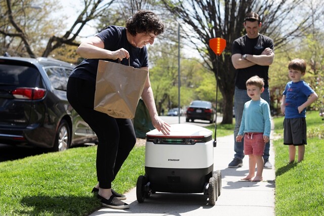 4월8일 미국 워싱턴주의 한 주민이 배달로봇으로부터 물품을 건네받고 있다. 연합뉴스